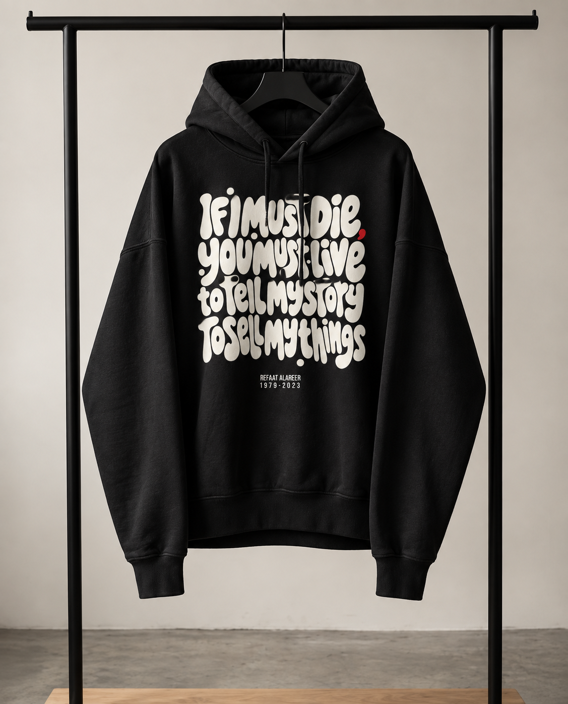 black hoodie on a rack with part of poem from poet from Gaza If I must Die, you must live
