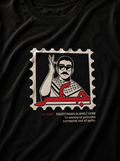 A close-up of a black t-shirt featuring a graphic print of a postage stamp. The stamp contains a stylized illustration of a man raising his hand, with red Arabic calligraphy and the text '*JA-KAR' 'PALESTINIAN SLANG | VERB To annoy or provoke someone out of spite.