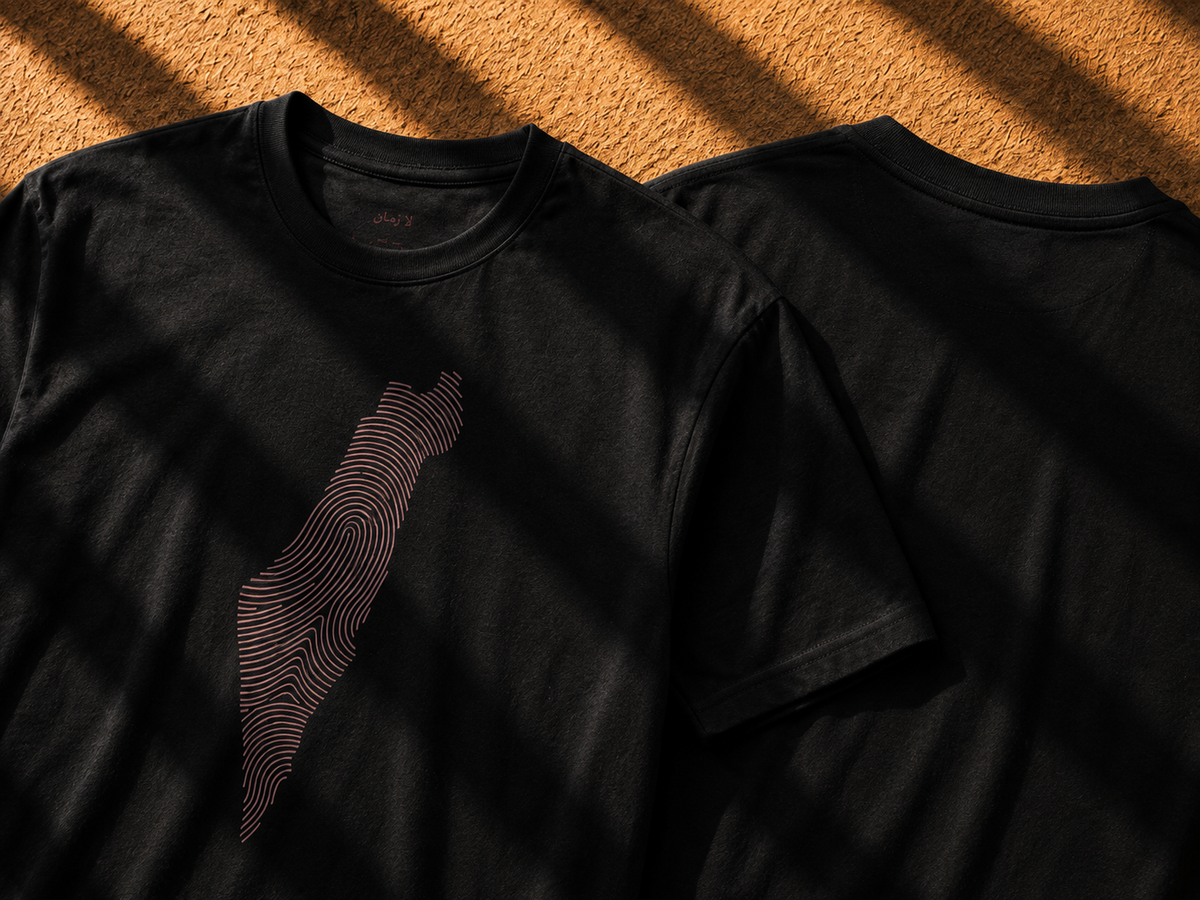 Two black short-sleeve crewneck t-shirts displayed on a textured orange-brown surface under dramatic diagonal shadows. The front shirt features a graphic of the island of Taiwan rendered in concentric wavy lines.