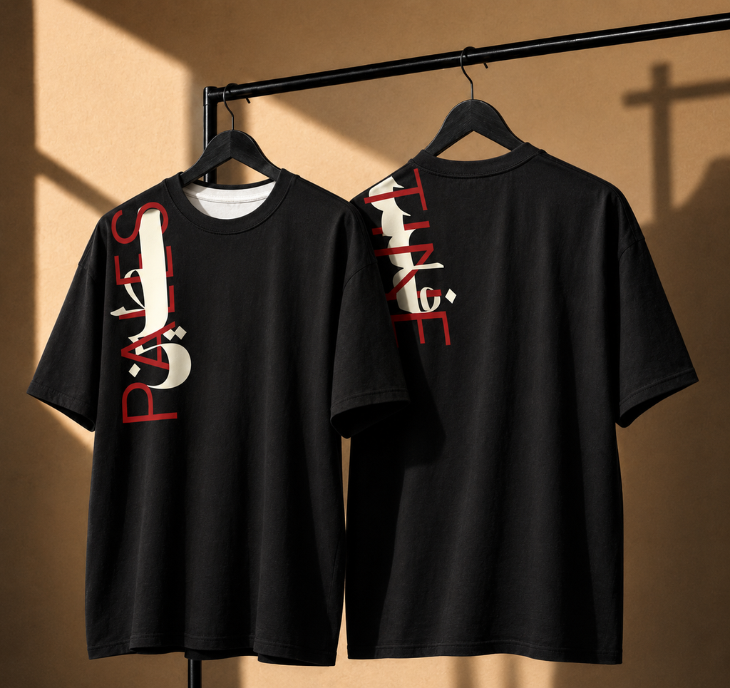 Two black short-sleeve T-shirts hanging on black hangers from a clothing rack, showing front and back views. The front shirt has a large vertical white graphic with red text on the left chest, and the back shirt has a large vertical white graphic with red text on the right chest.