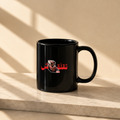 A glossy black ceramic mug with a red and white graphic print of Deadpool and Arabic text, sitting on a light beige stone ledge with diagonal window shadows cast across the background.